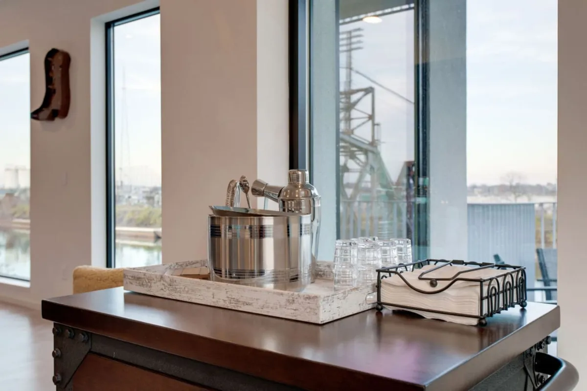 A stylish arrangement of glassware and an ice bucket atop a wooden tray, set in a relaxed, social atmosphere. The image suggests opportunities for pre- or post-nightlife gatherings at home, with friends toasting and sharing memories.