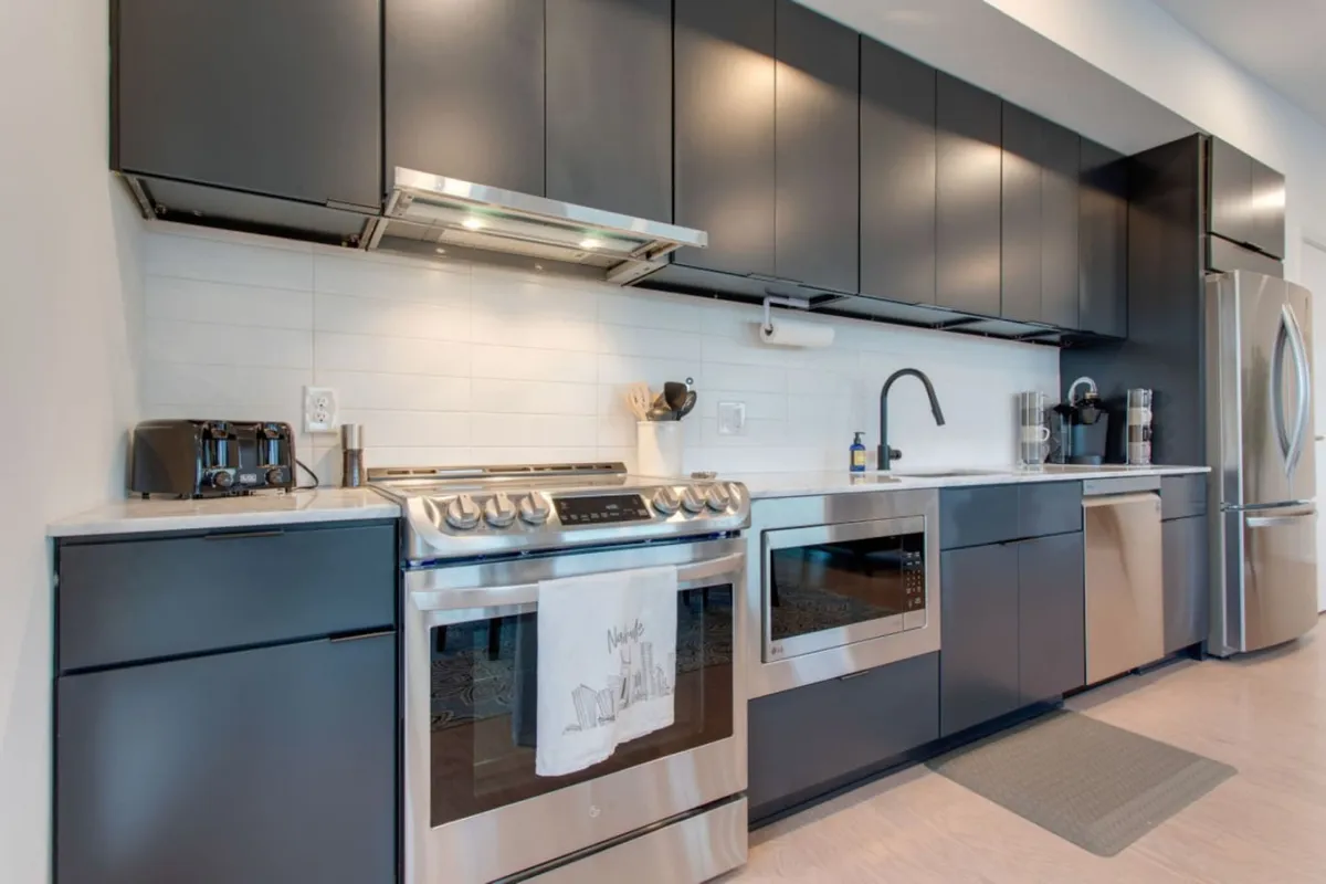 A modern kitchen featuring stainless steel appliances, sleek cabinetry, and clean countertops. The space is well-lit and exudes a contemporary vibe that invites culinary creativity. The clear view of ample counter space and high-quality cooking equipment signals functionality and style, perfect for both casual cooking and hosting.